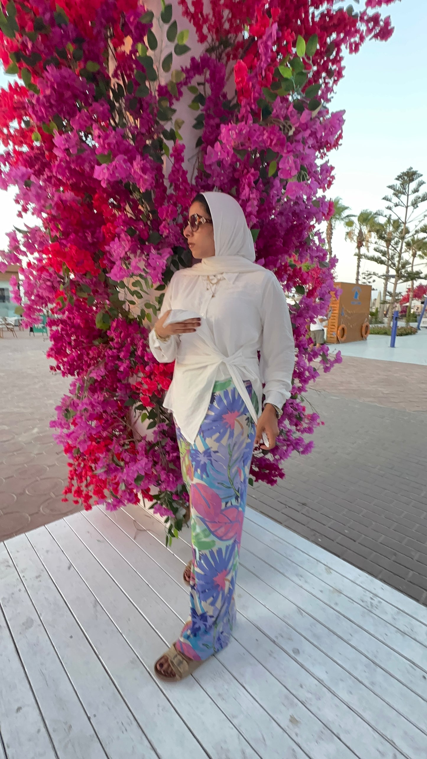 Woman in a colorful outfit standing in front of a vibrant floral arch.